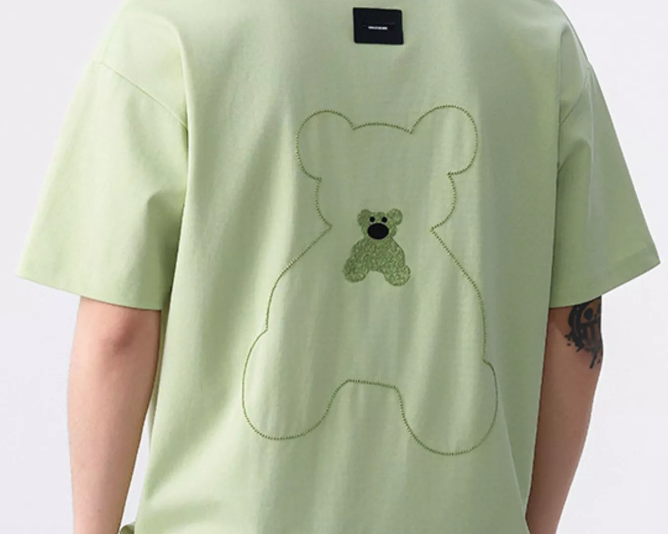 NEWYORKLISTED ATLAS MEN'S COLLECTION: Person wearing a light green t-shirt with a bear design on the back against a white background