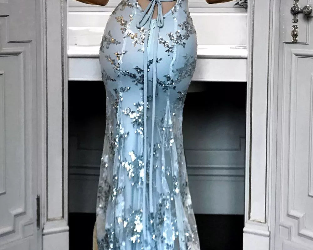 Woman wearing a light blue floral evening gown in a room with white walls and doors.