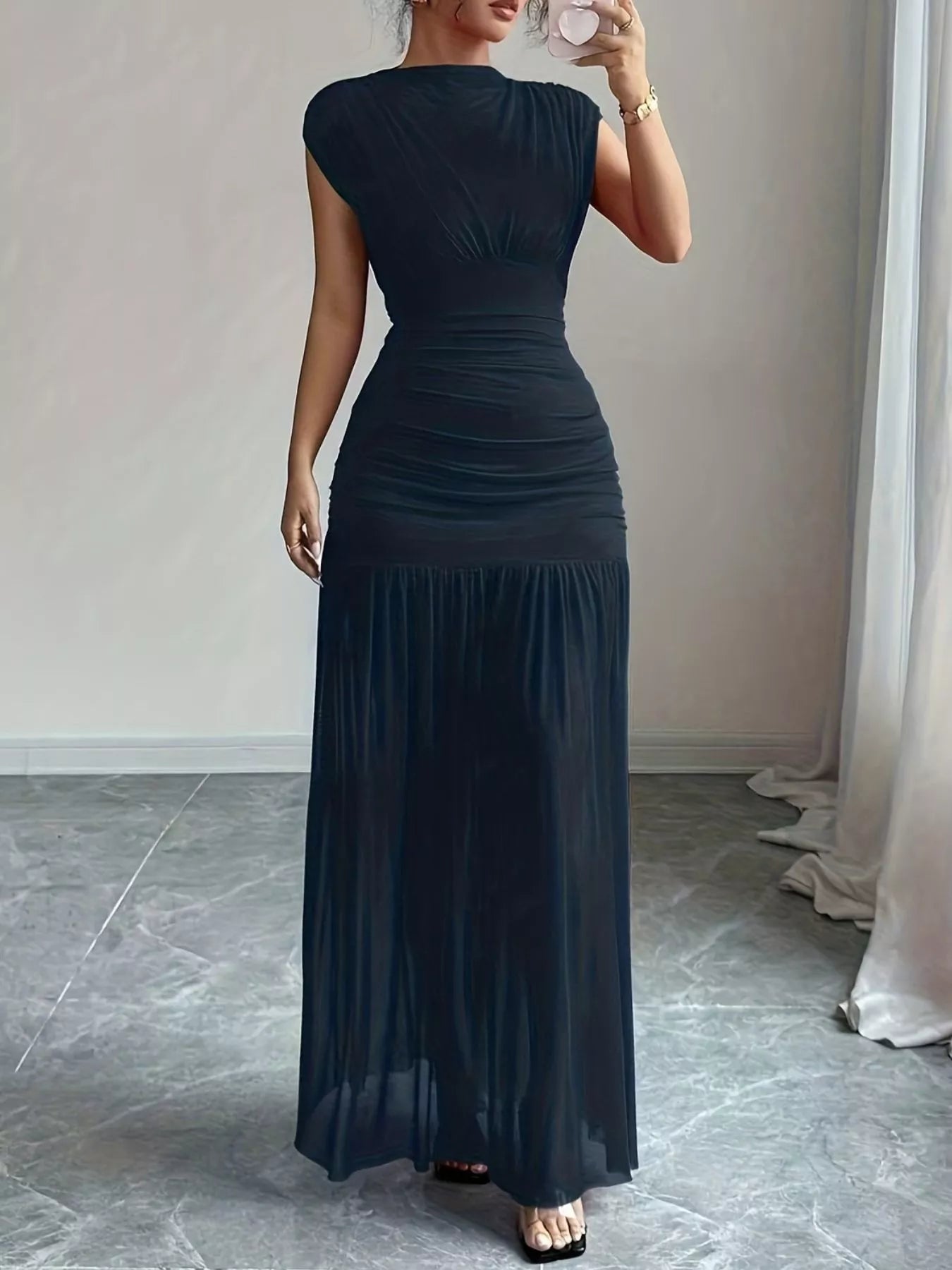 NEWYORKLISTED STYLE COLLECTION: Woman wearing a long black dress in a room with a neutral background