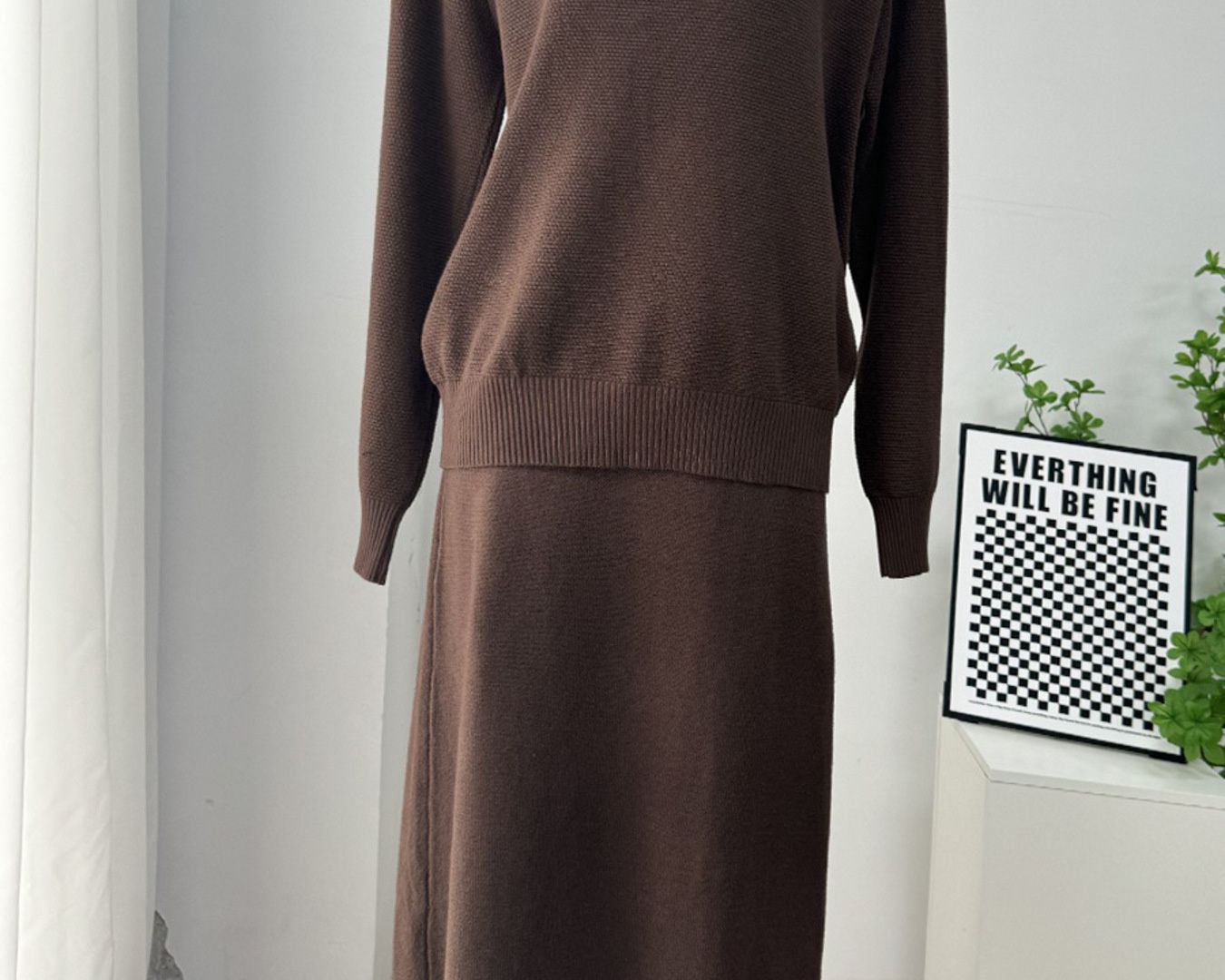NEWYORKLISTED Comfort Collection: Brown two-piece outfit on a mannequin against a white wall with a framed quote.
