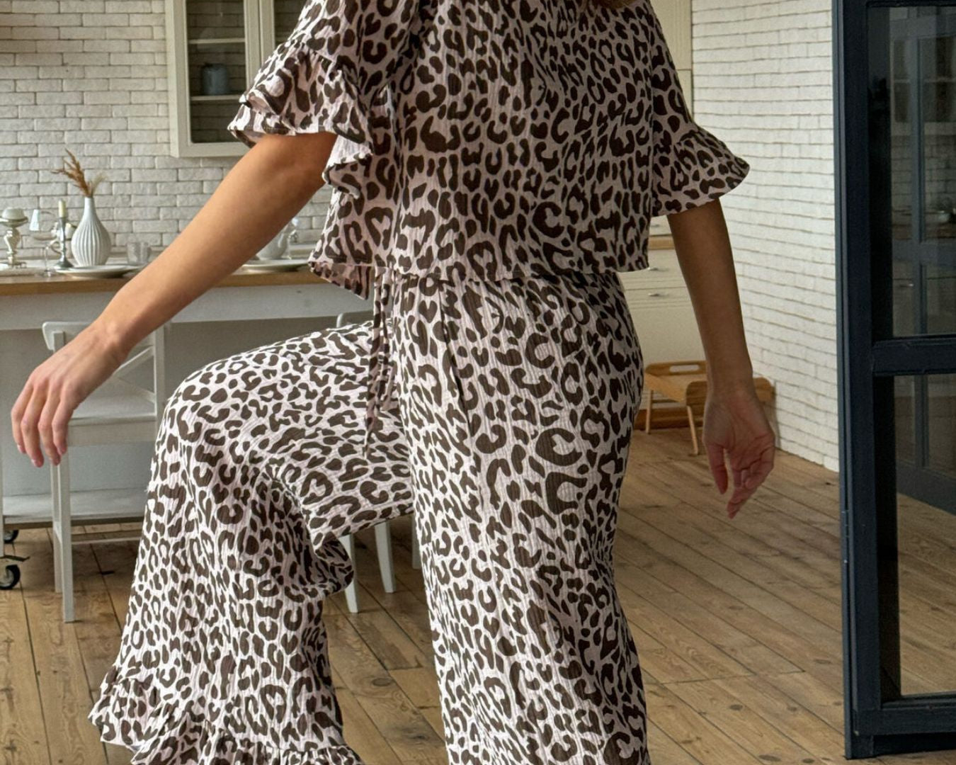 NEWYORKLISTED Intimate Apparel Collection: Leopard Print Ruffle Trim Top and Pants Lounge Set: Woman wearing a leopard print outfit in a home setting