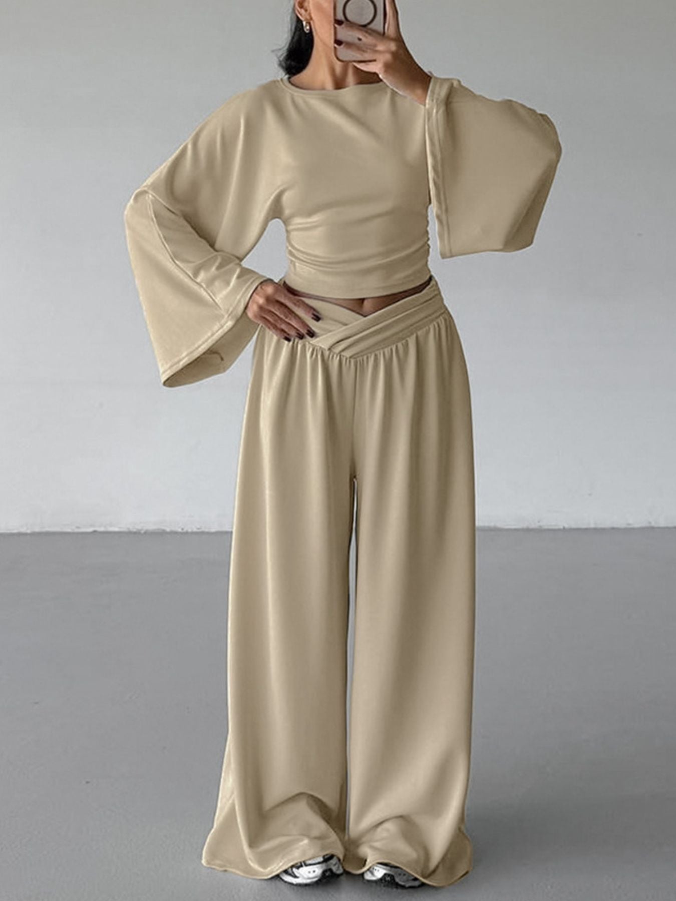 NEWYORKLISTED STYLE COLLECTION: Person wearing a beige outfit with wide sleeves and high-waisted pants against a plain background