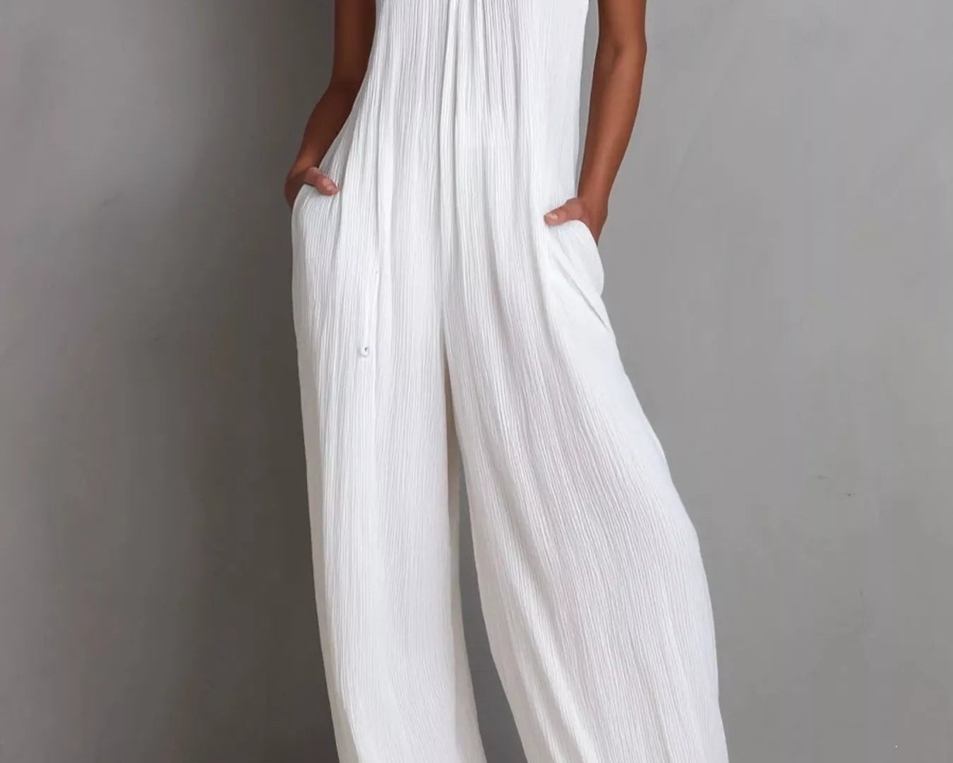 NEWYORKLISTED STYLE COLLECTION: Woman wearing a white halter neck jumpsuit against a gray background