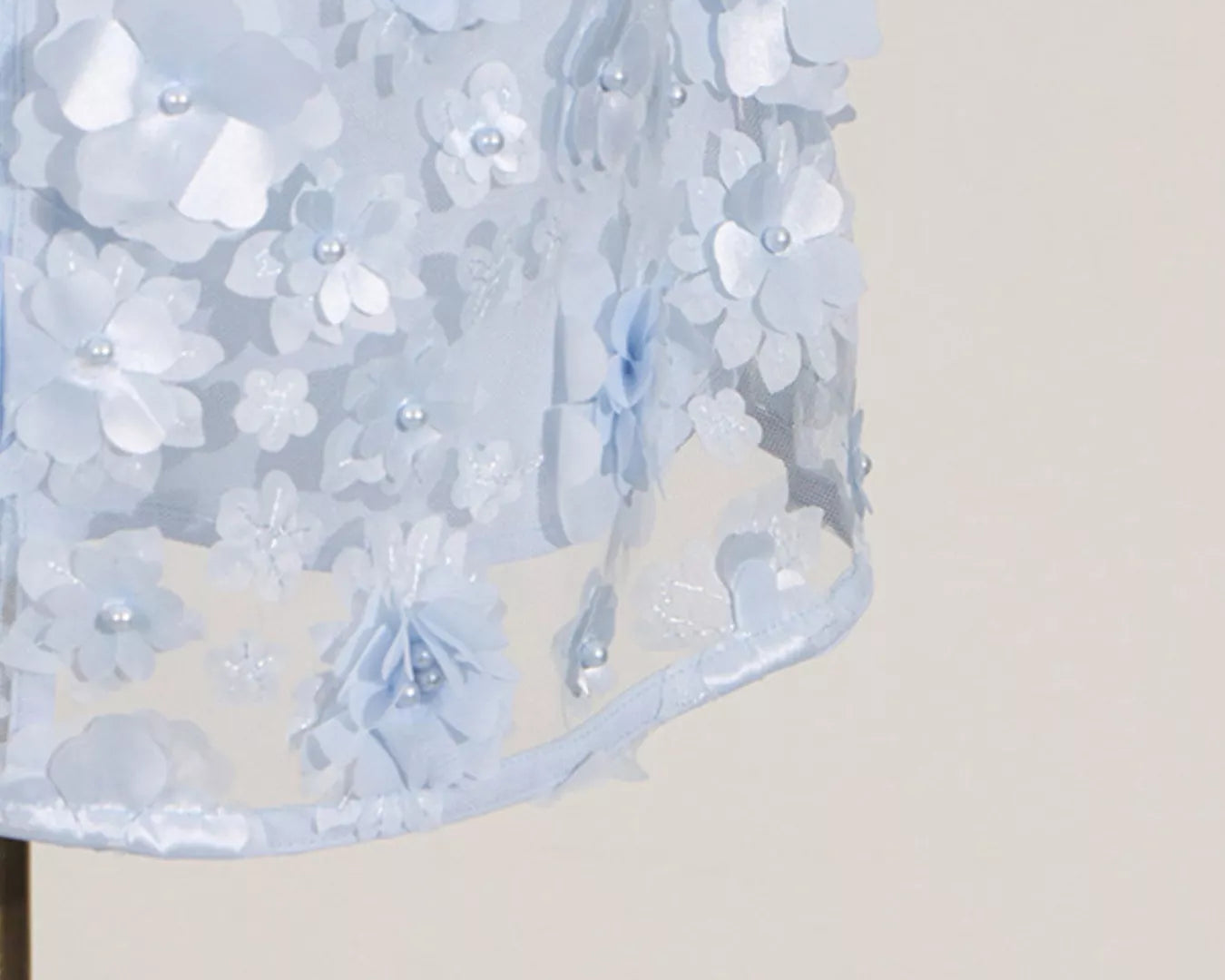 NEWYORKLISTED STYLE COLLECTION: Close-up of a light blue floral dress on a mannequin against a beige background