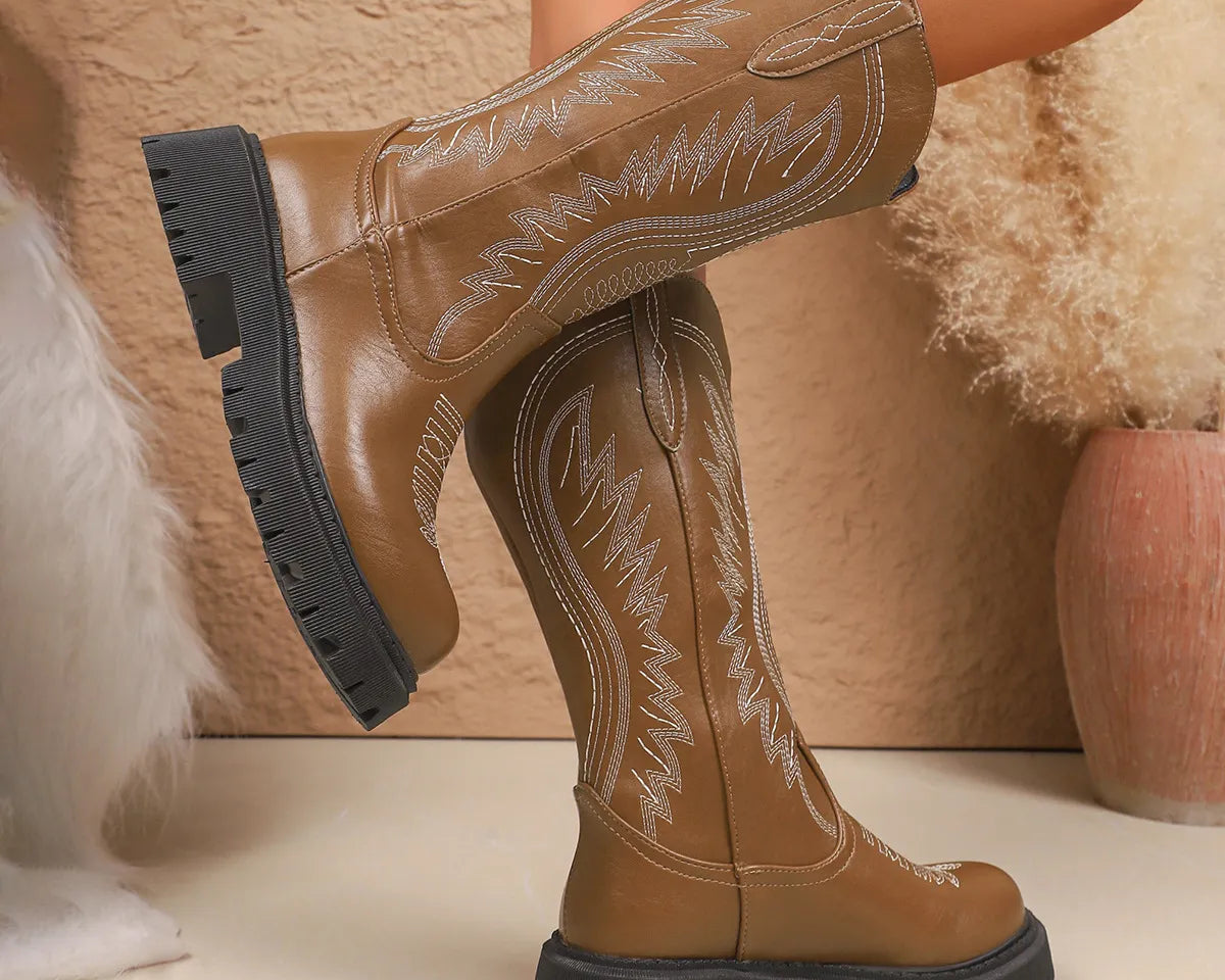 NEWYORKLISTED SHOE COLLECTION: Round Toe Block Heels Boots: Brown cowboy boots with black soles worn by a person, against a neutral background.