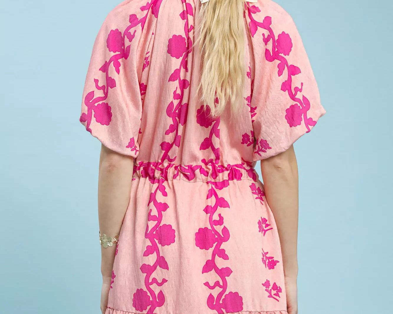 NEWYORKLISTED STYLE COLLECTION: Woman wearing a pink floral dress against a light blue background
