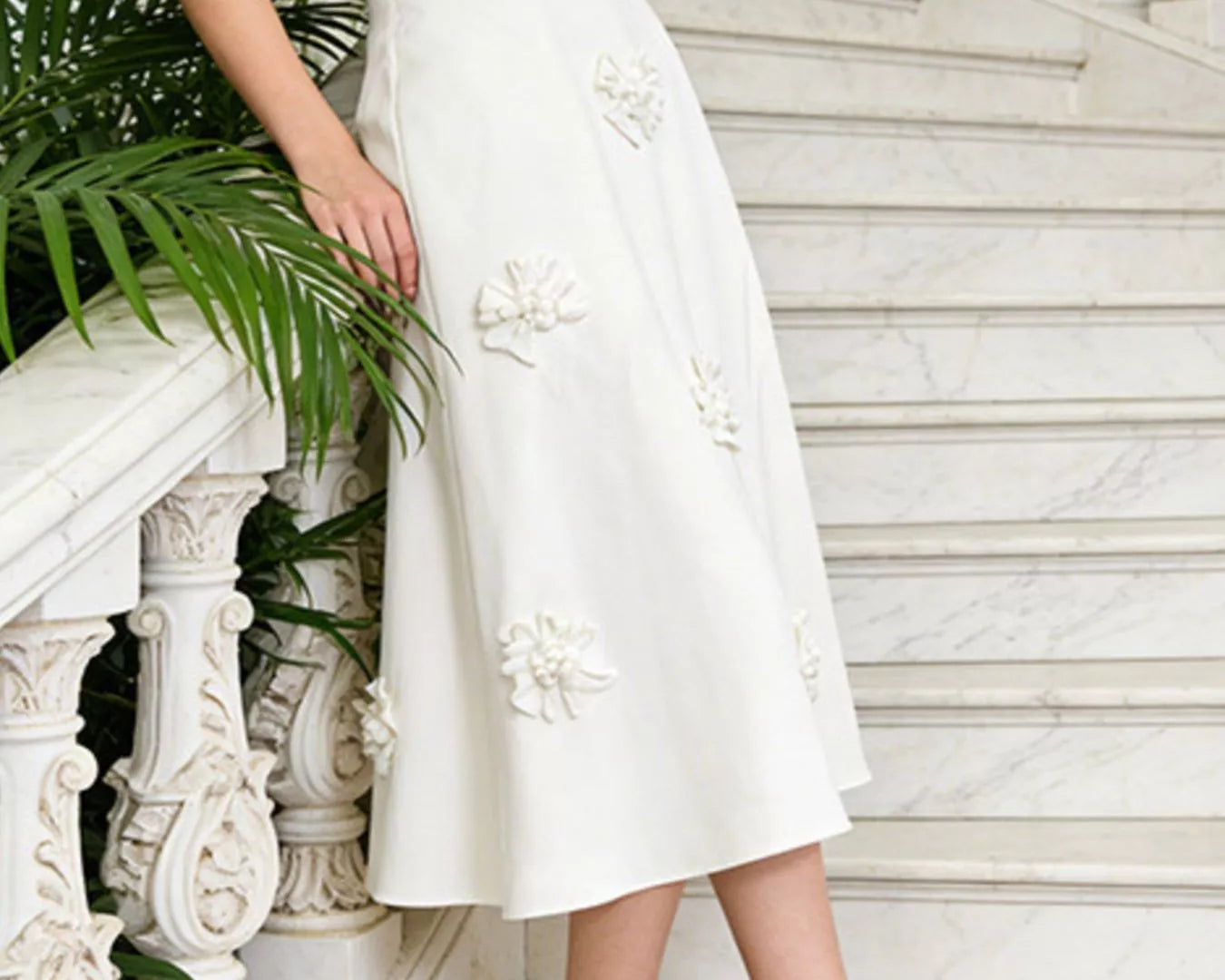 NEWYORKLISTED STYLE COLLECTION: Floral Embellished Midi Skirt -Person wearing a white skirt with floral embroidery on a marble staircase.