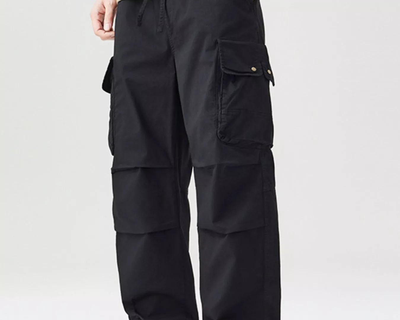 NEWYORKLISTED ATLAS MEN'S COLLECTION: Model wearing black cargo pants and a beige shirt on a white background