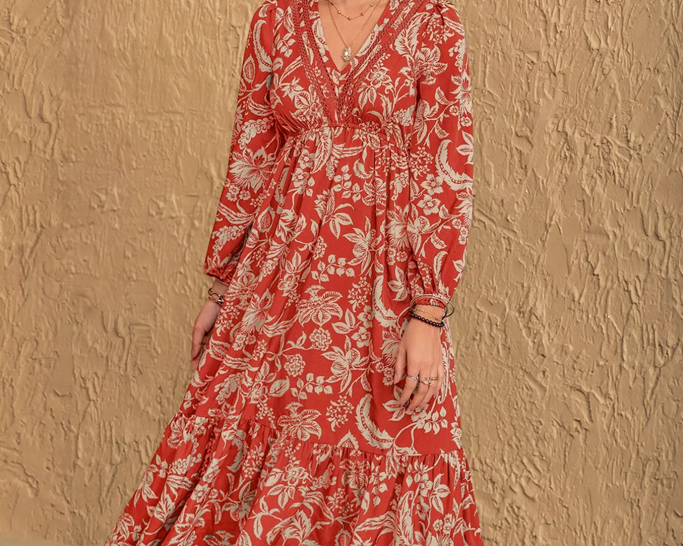 NEWYORKLISTED STYLE COLLECTION: Woman wearing a red floral dress against a beige wall