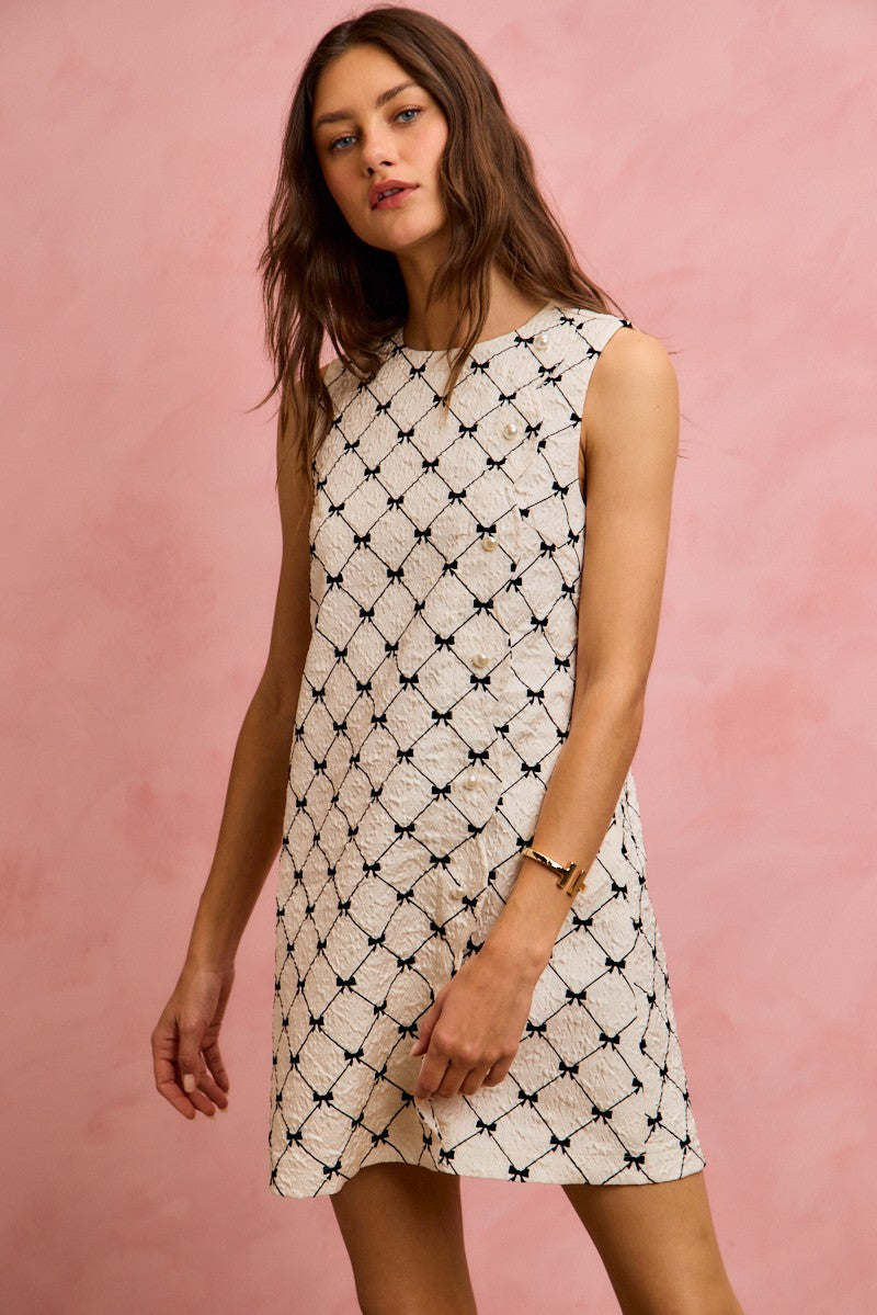 NEWYORKLISTED STYLE COLLECTION: Woman wearing a white dress with black pattern against a pink background