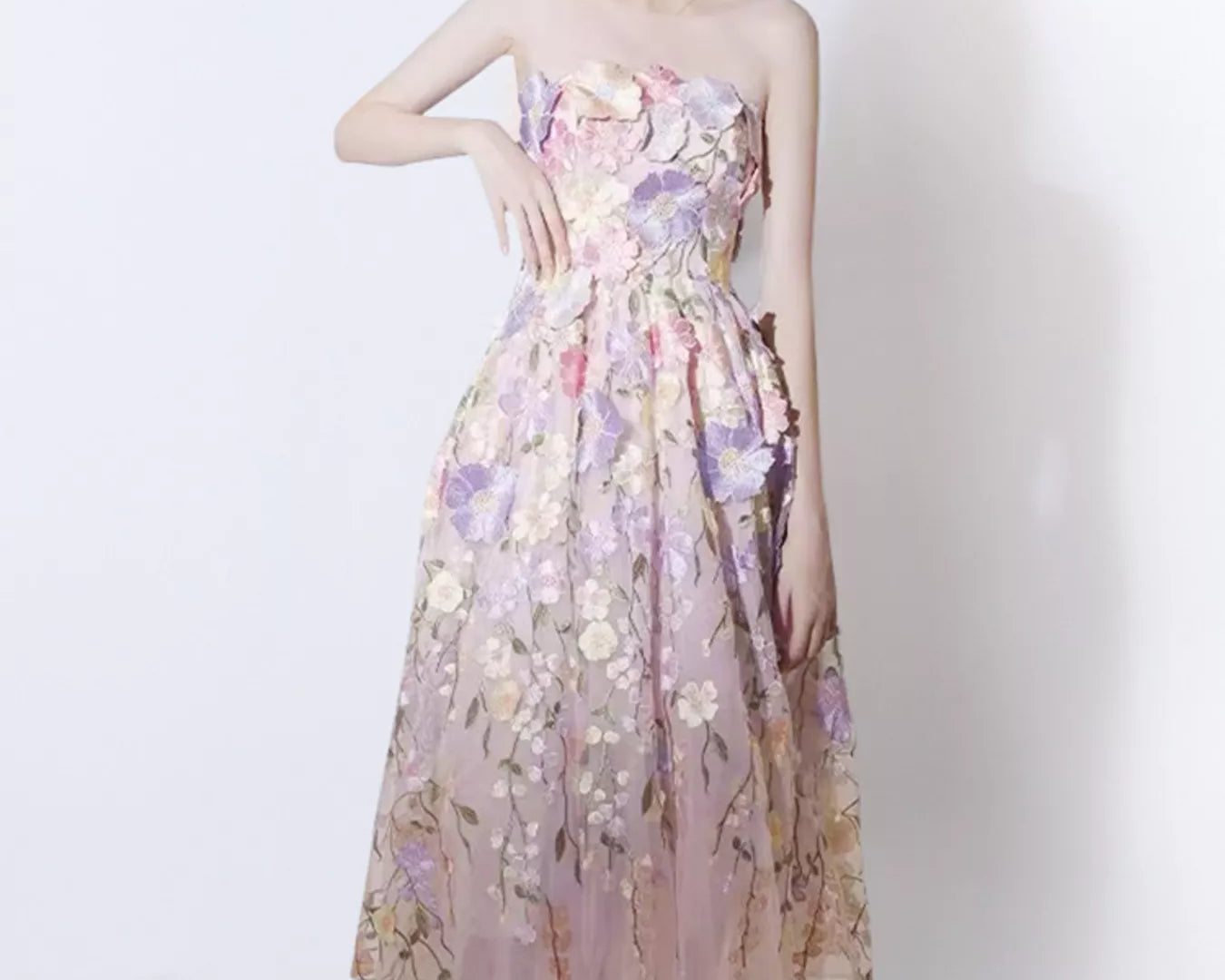 NEWYORKLISTED STYLE COLLECTION: Woman wearing a floral strapless dress against a white background