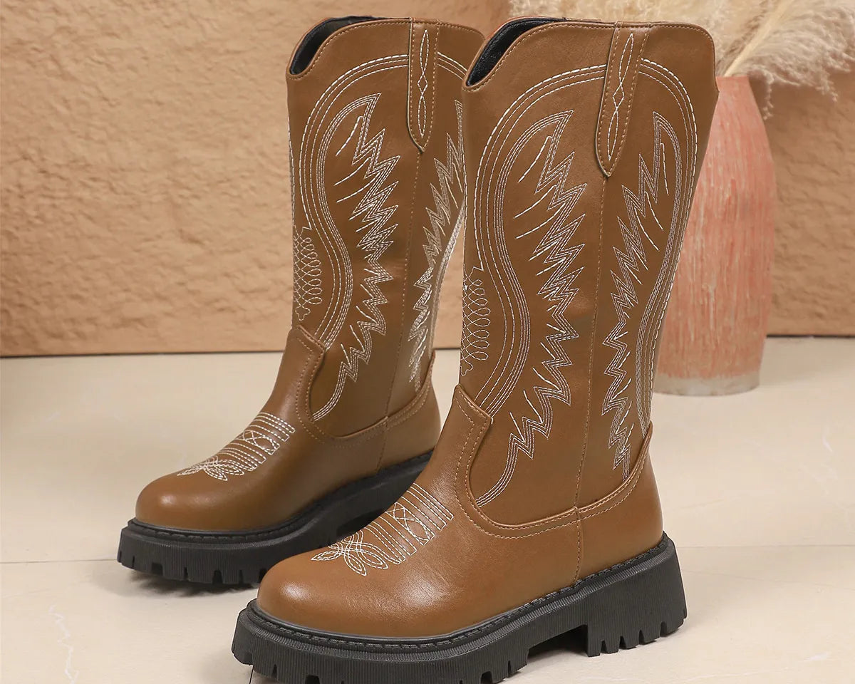 NEWYORKLISTED SHOE COLLECTION: Round Toe Block Heels Boots: Pair of brown cowboy boots with detailed stitching on a beige background