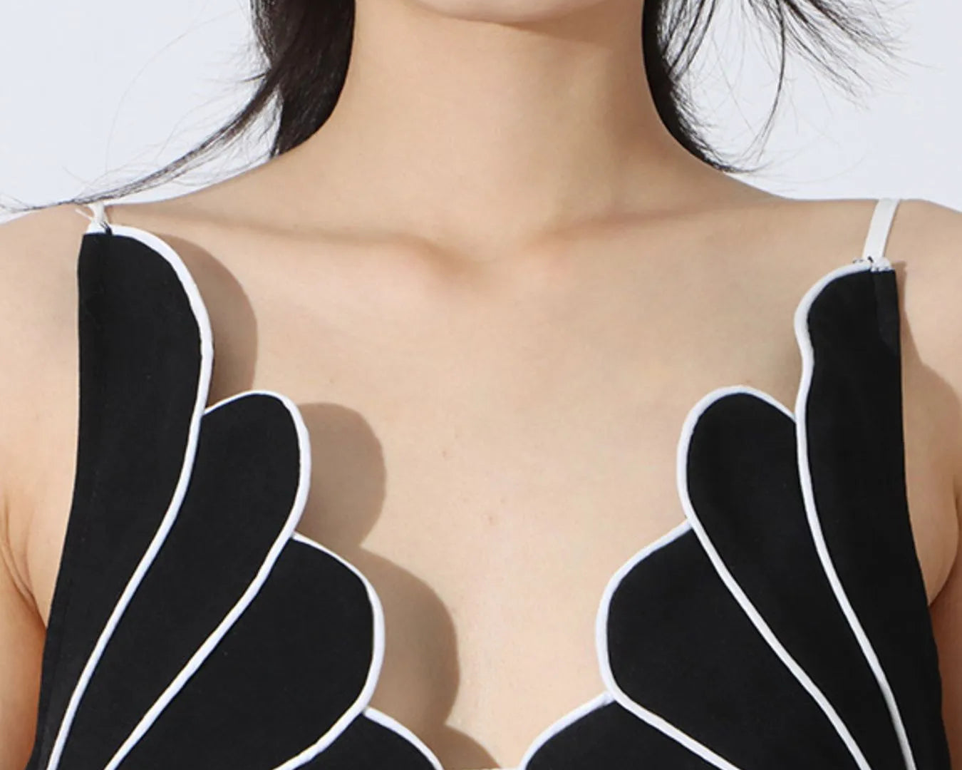 NEWYORKLISTED: Person wearing a black and white sleeveless top with unique design on a white background