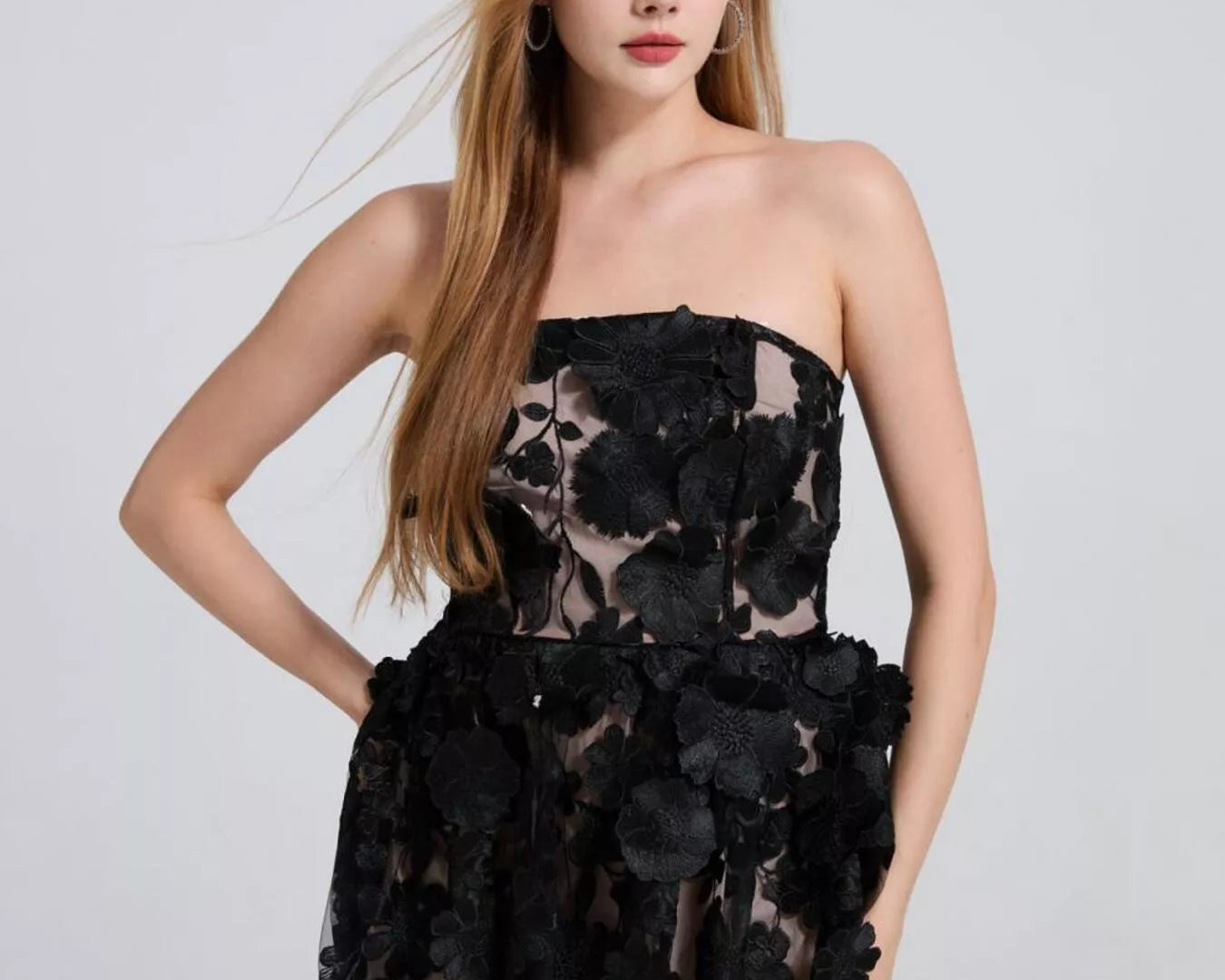 NEWYORKLISTED STYLE COLLECTION: Woman wearing a black floral strapless dress on a light gray background
