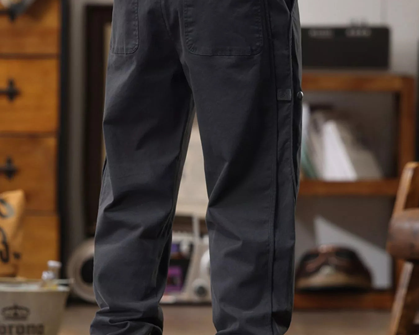 NEWYORKLISTED ATLAS MEN'S COLLECTION: Person wearing dark cargo pants and yellow boots in a room with wooden furniture.