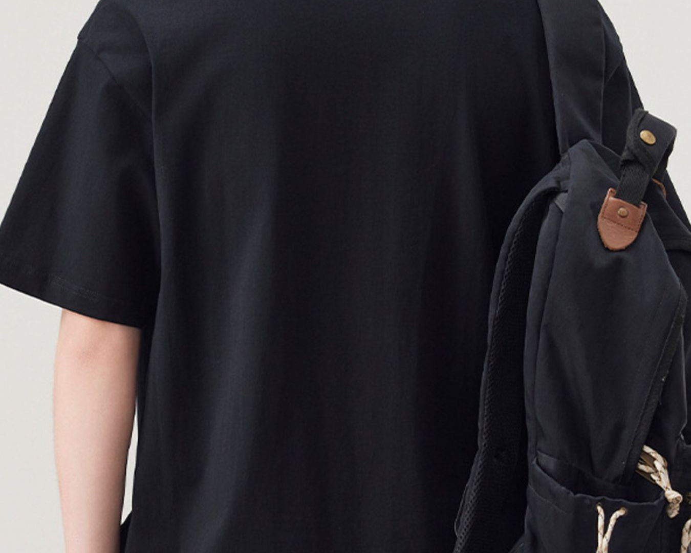 NEWYORKLISTED ATLAS MEN"S COLLECTION: Person wearing a black t-shirt and carrying a black backpack on a plain background