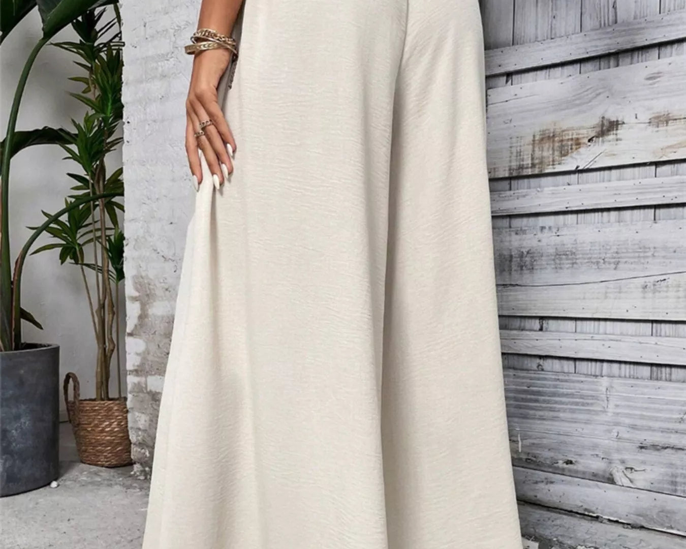 NEWYORKLISTED: Person wearing a long beige skirt standing against a wooden paneled wall.