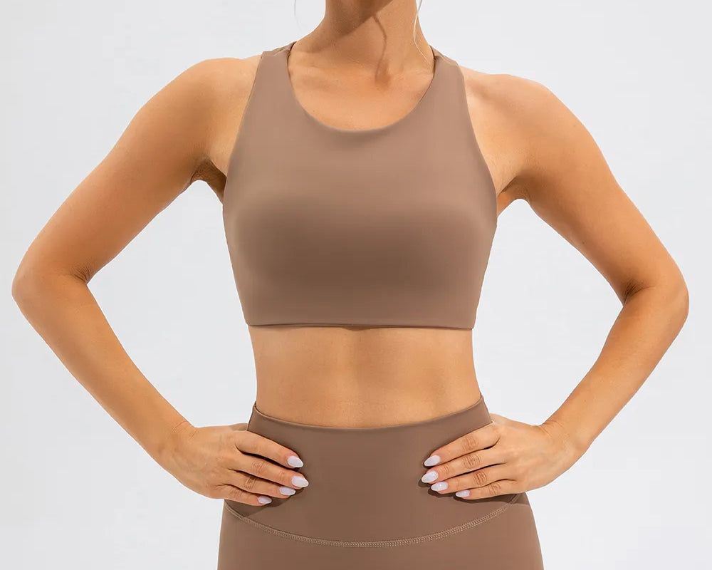 NEWYORKLISTED ACTIVEWEAR COLLECTION: Woman wearing a brown sports bra and leggings on a light gray background