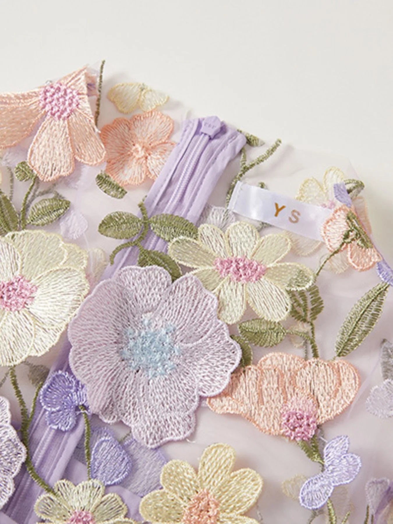 NEWYORKLISTED STYLE COLLECTION: Embroidered floral designs on fabric with a visible brand tag.