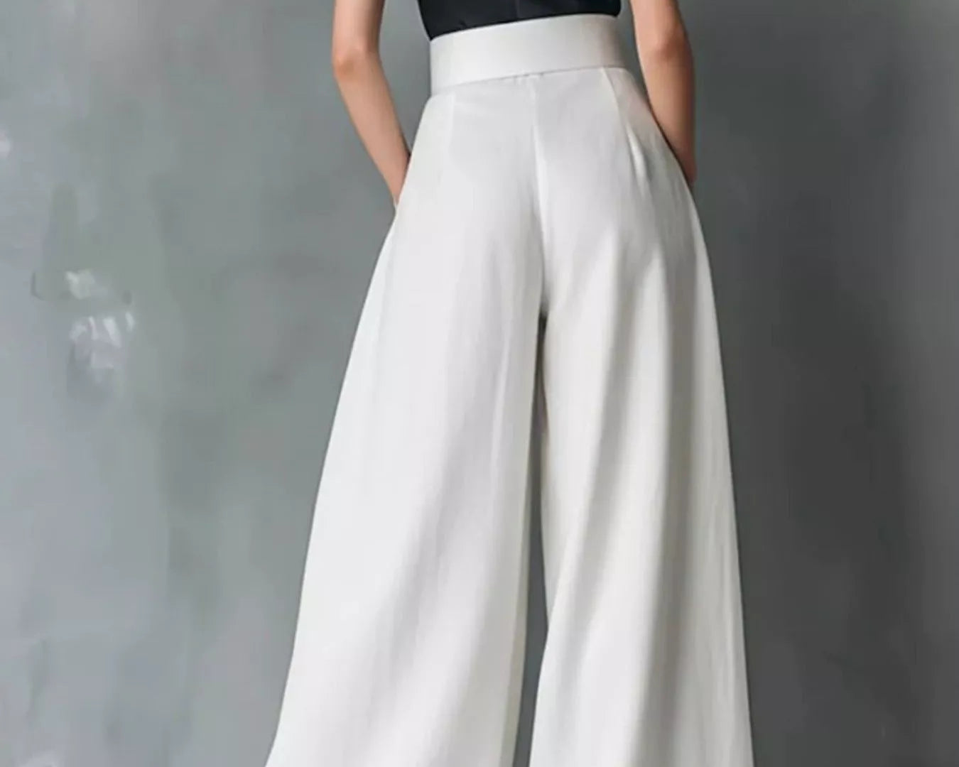 NEWYORKLISTED STYLE COLLECTION: Person wearing a black top and white wide-leg pants against a gray background