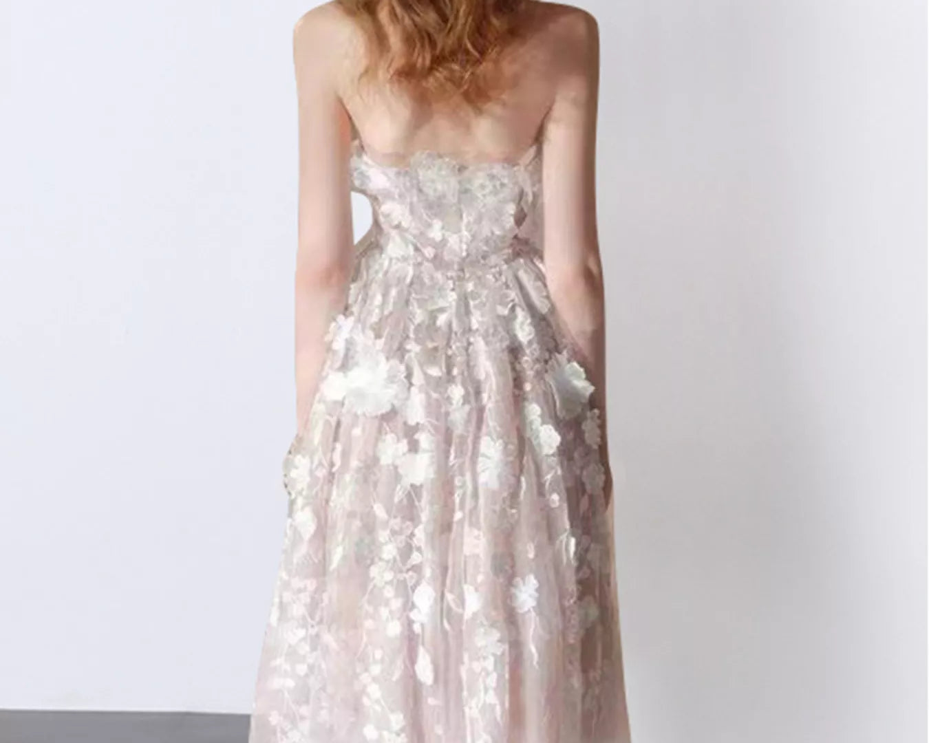 NEWYORKLISTED STYLE COLLECTION: Woman wearing a strapless floral dress against a white background