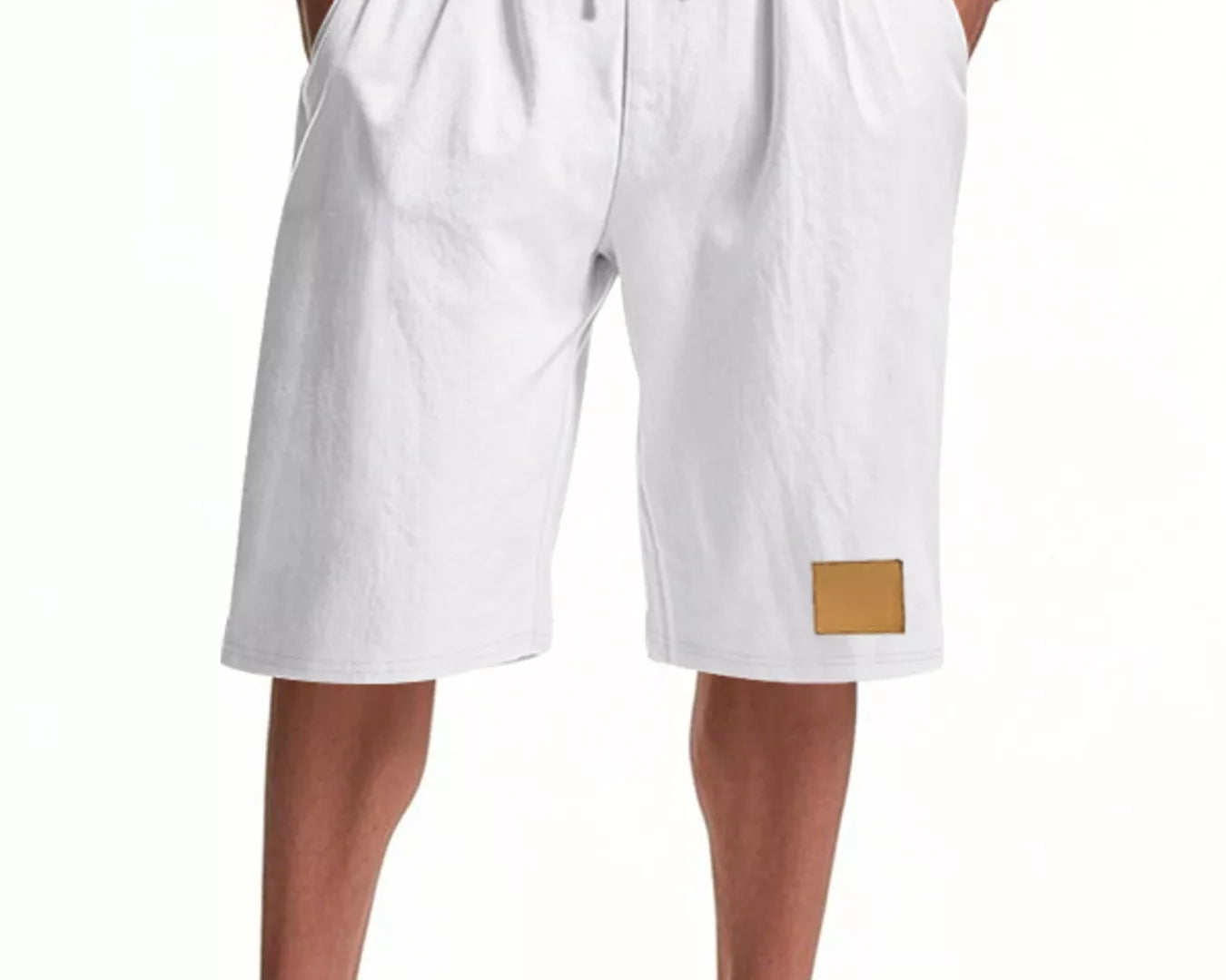 NEWYORKLISTED ATLAS MEN'S COLLECTION: White shorts with a gold patch worn by a person on a white background