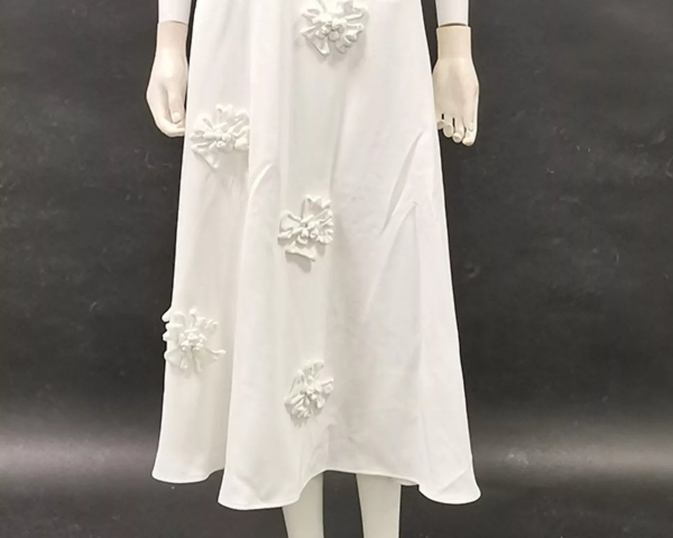 NEWYORKLISTED STYLE COLLECTION: Mannequin wearing a white dress with floral embellishments on a dark background