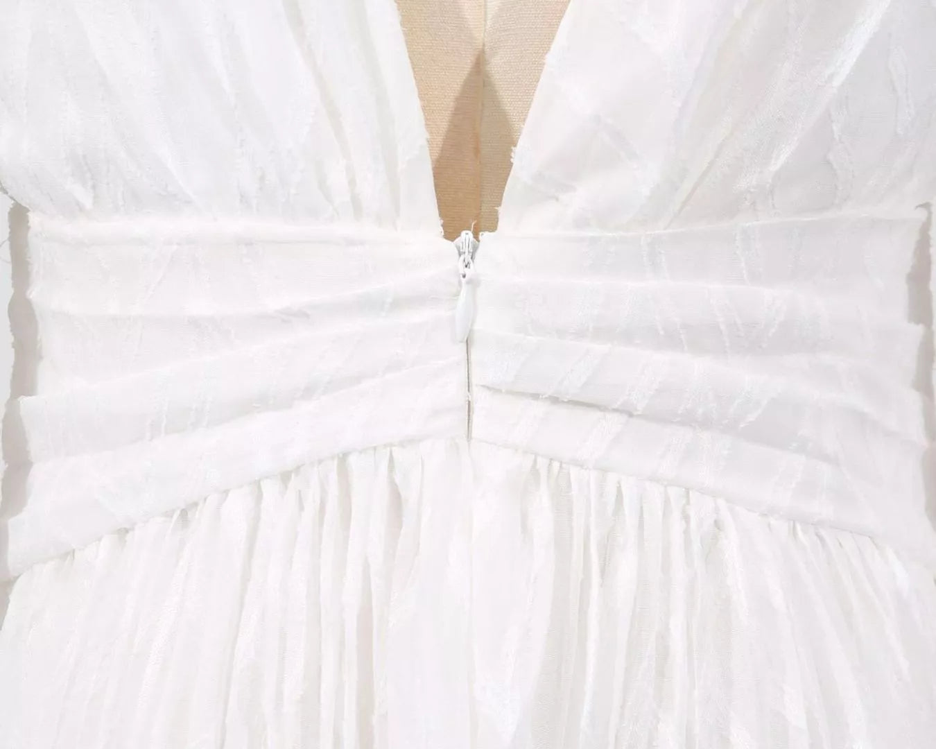 NEWYORKLISTED STYLE COLLECTION: Close-up of a white dress with a deep neckline and bow detail.