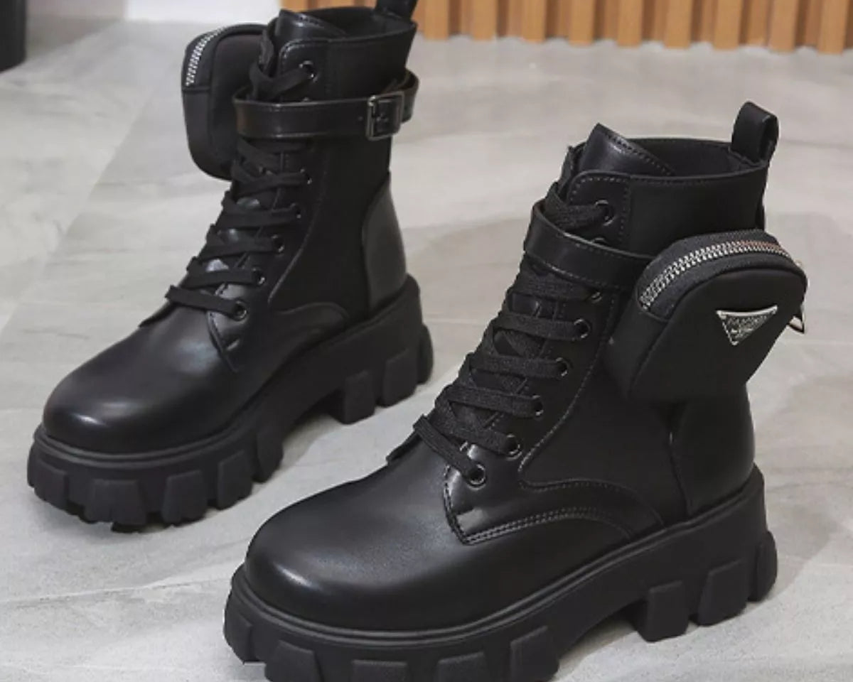 NEWYORKLISTED SHOE COLLECTION: Pair of black leather boots with chunky soles on a light gray surface.