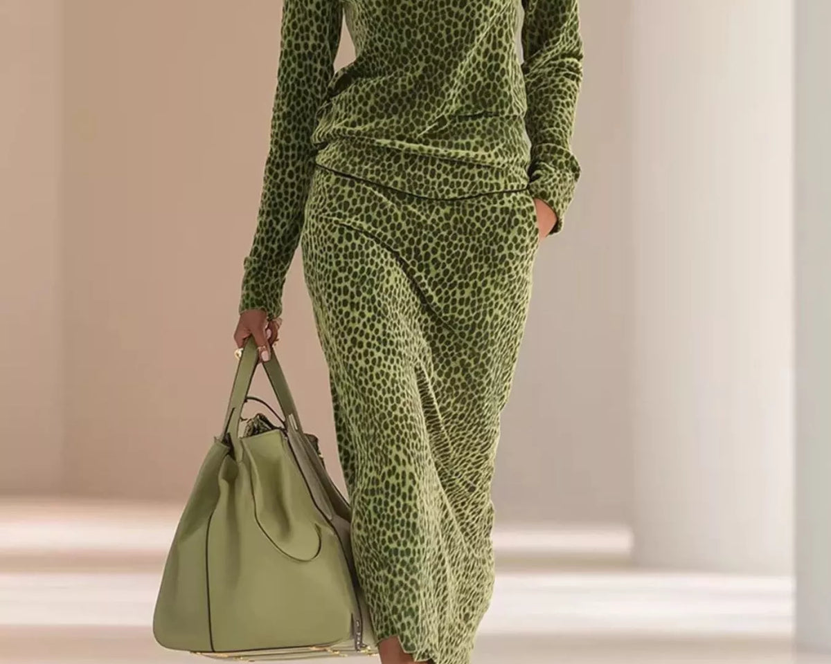 NEWYORKLISTED STYLE COLLECTION: A model walks in a runway setting wearing a matching olive green leopard-print mock-neck long-sleeve top and midi skirt set, holding a matching green leather handbag.