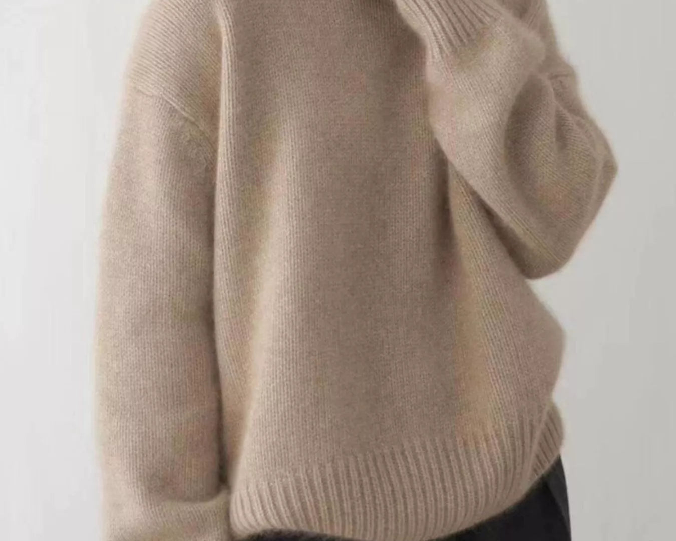 Person wearing a beige sweater against a plain background