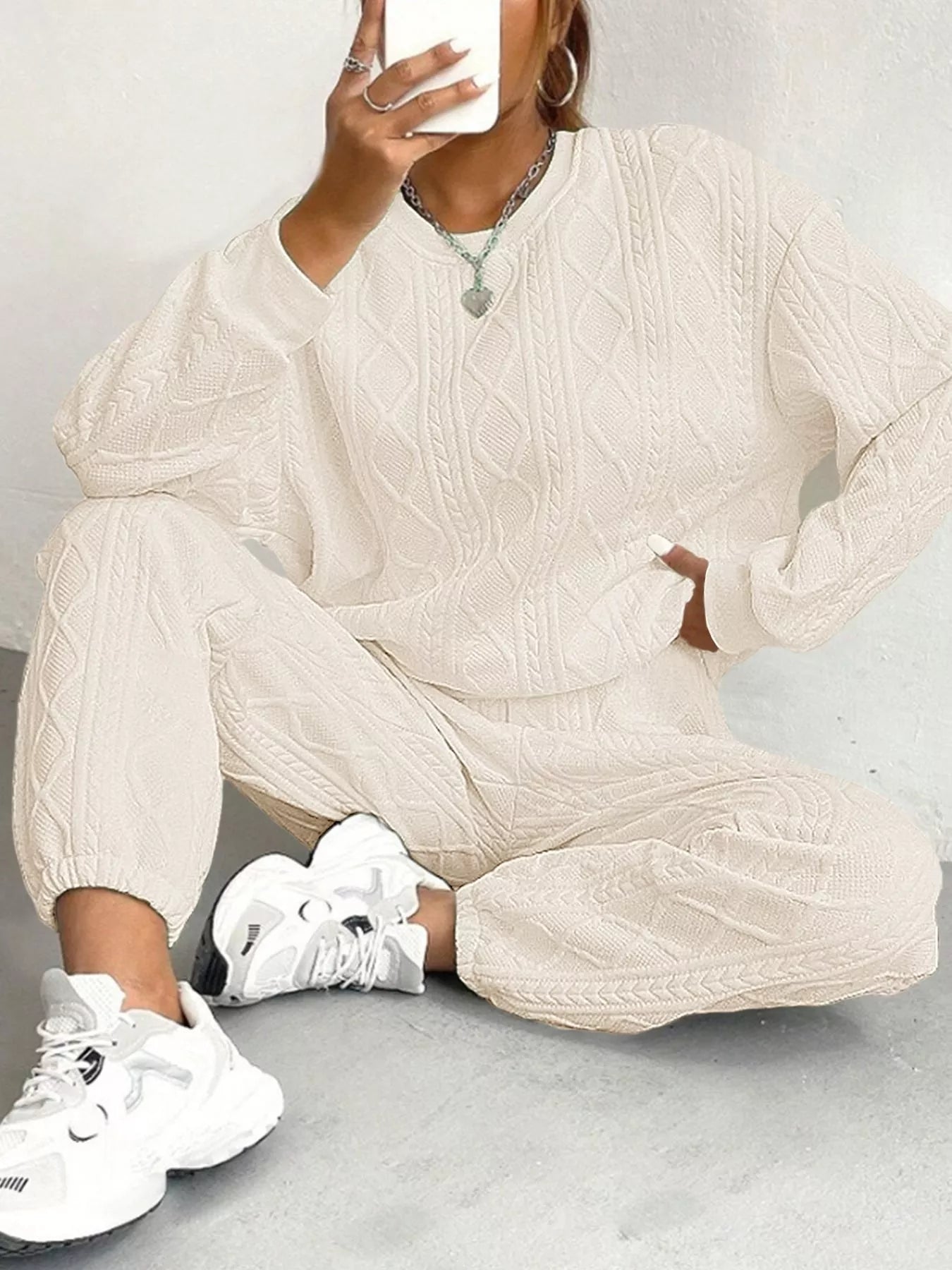 NEWYORKLISTED COMFORT COLLECTION: Person wearing a beige cable knit outfit with white sneakers on a light gray background