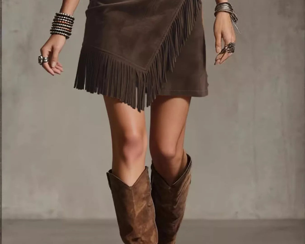 NEWYORKLISTED STYLE COLLECTION: Person wearing a brown suede skirt with fringe and matching knee-high boots on a neutral background