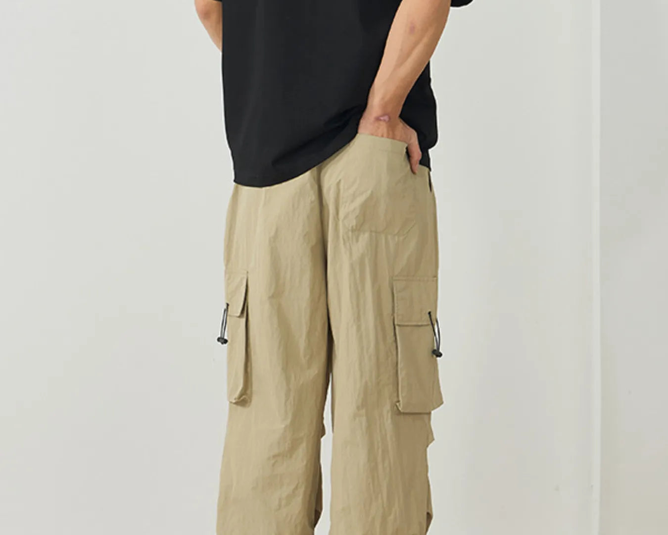 NEWYORKLISTED ATLAS MEN's Collection: Person wearing beige cargo pants and a black shirt on a plain background