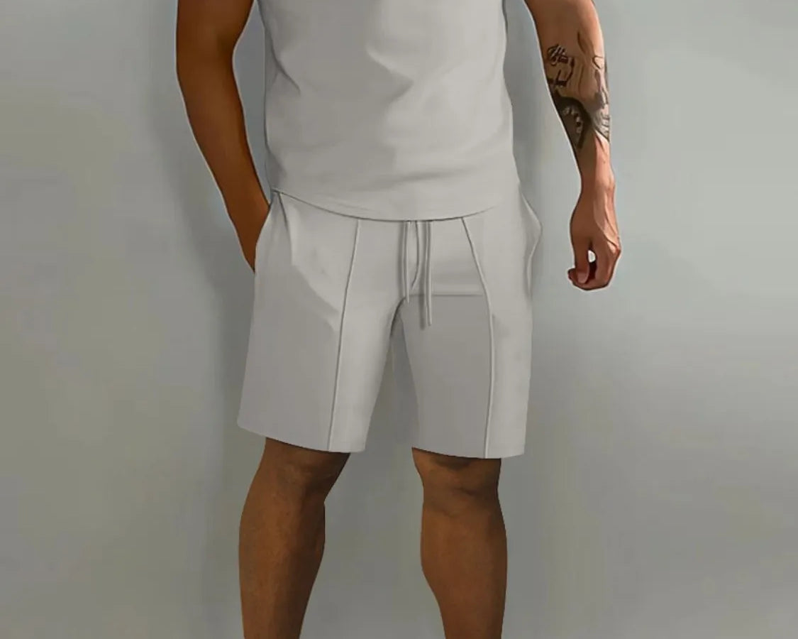 NEWYORKLISTED ATLAS MEN's COLLECTION: Male model wearing a gray polo shirt and shorts set with white sneakers on a plain background