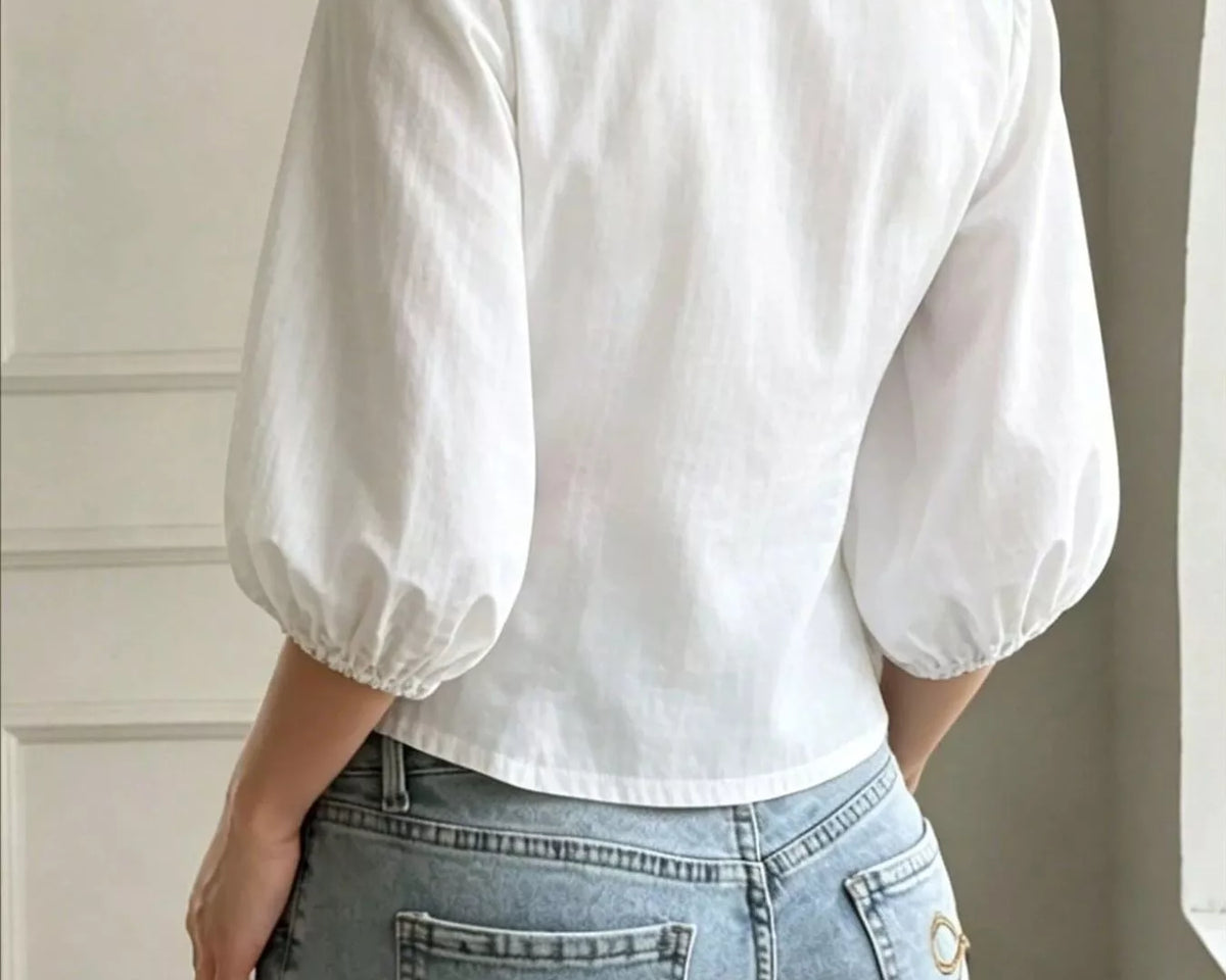 NEWYORKLISTED STYLE COLLECTION: A woman shown from the back wearing a white puff-sleeve collared blouse tucked into light-wash blue jeans with decorative bow embroidery on the back pockets.