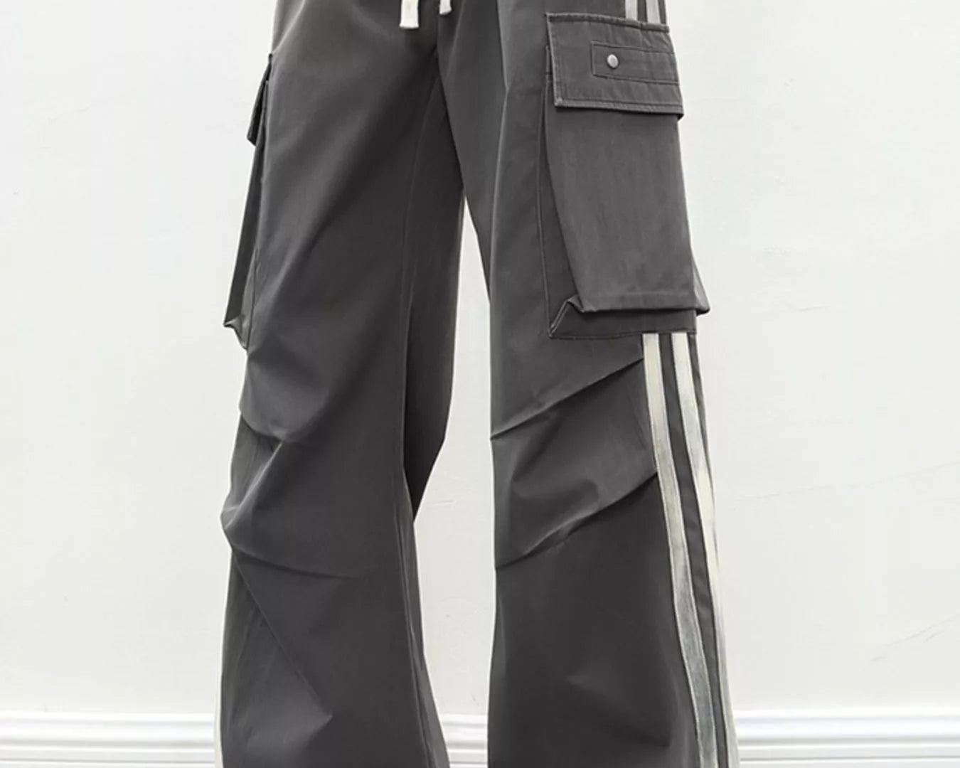 NEWYORKLISTED ATLAS MEN's COLLECTION: Person wearing gray cargo pants with white stripes on a plain background