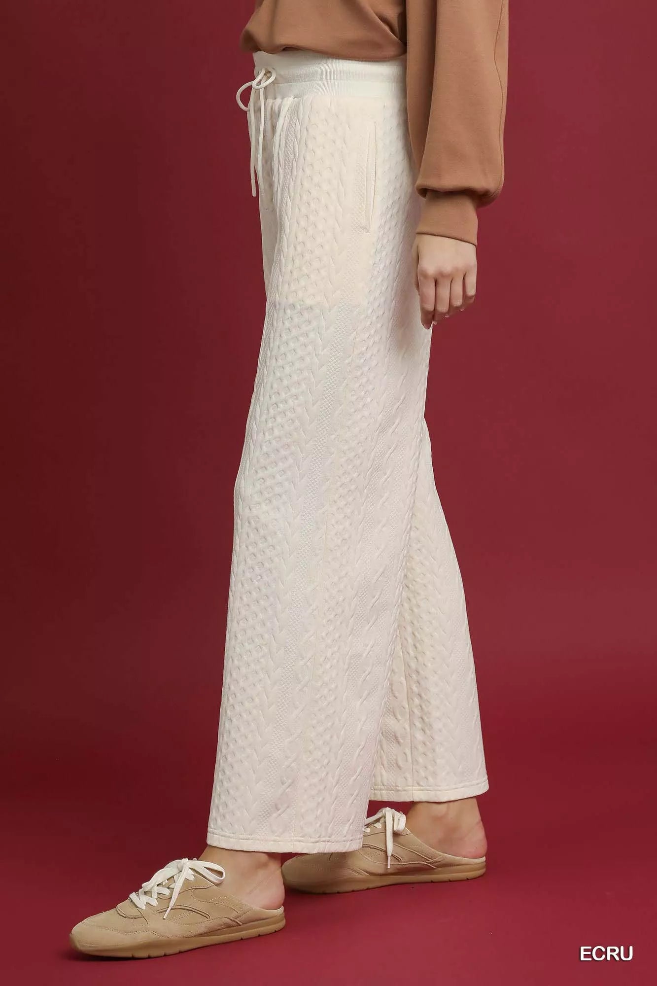 NEWYORKLISTED STYLE COLLECTION: Person wearing a textured white skirt with a brown top and shoes on a red background