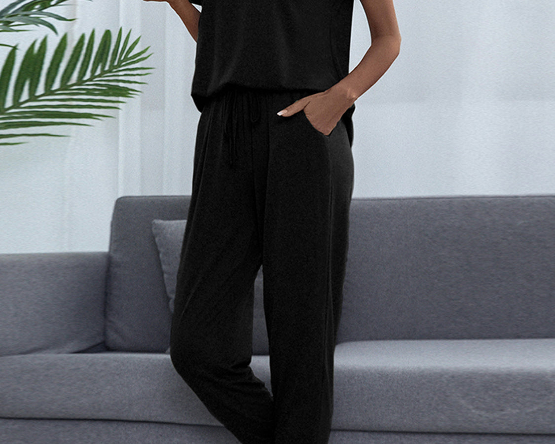 NEWYORKLISTED Intimate Apparel: Person wearing a black outfit sitting on a gray couch with a white wall and plant in the background