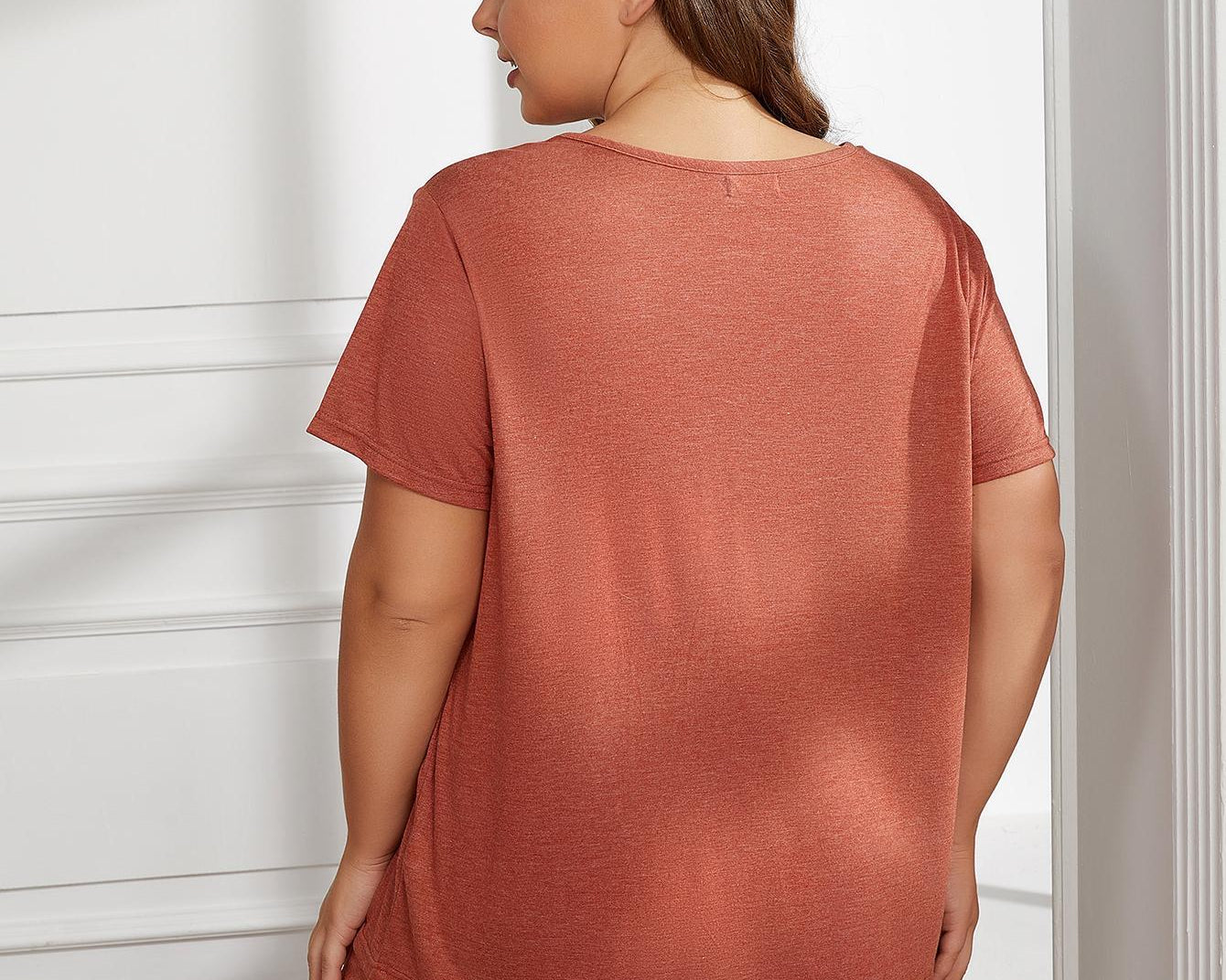 NEWYORKLISTED Intimate Apparel Collection: Woman wearing a rust-colored outfit standing in a room with white walls.