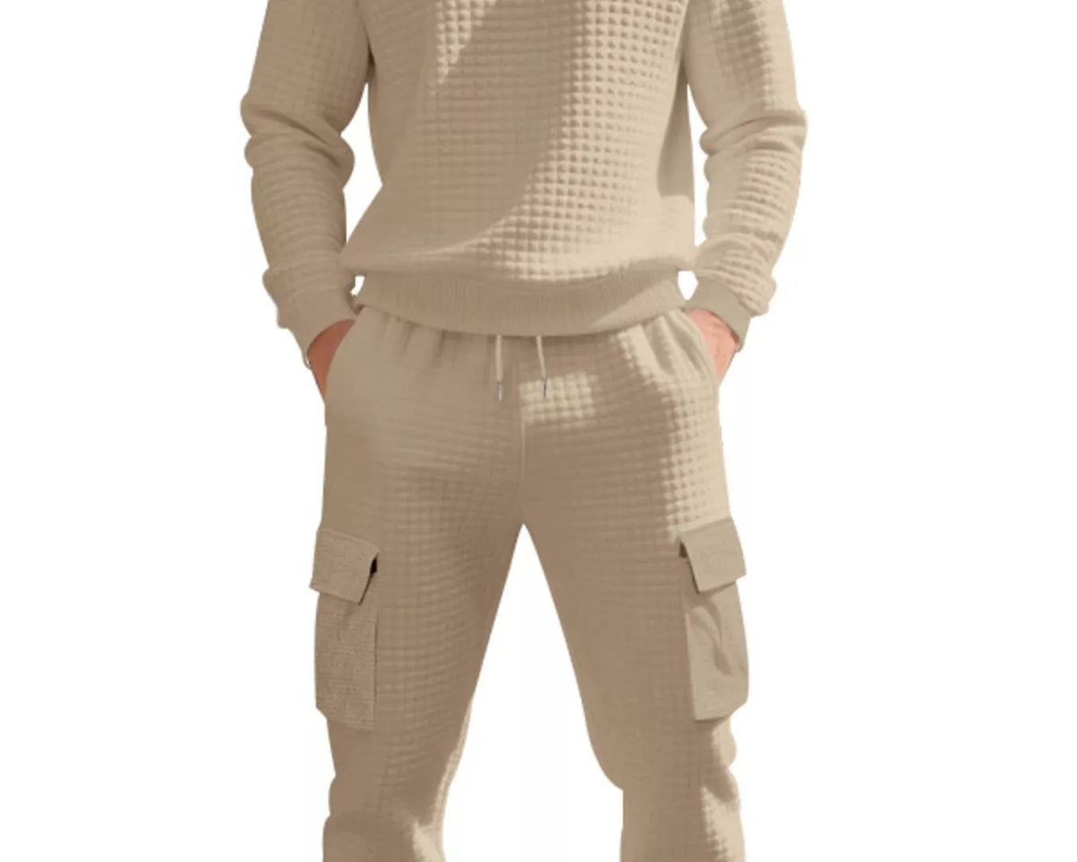 NEWYORKLISTED ATLAS MEN'S COLLECTION: A man wearing a matching beige waffle-knit lounge set, consisting of a long-sleeve crewneck sweatshirt and jogger pants with cargo pockets, shown against a plain white background.