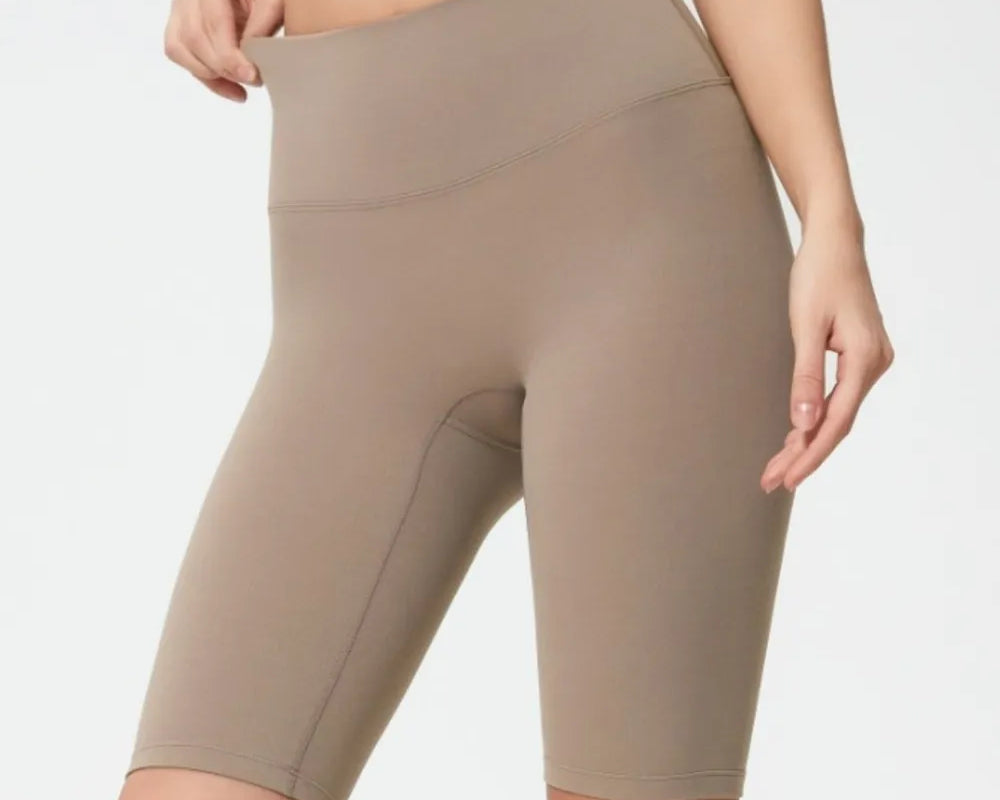 Person wearing beige athletic shorts on a plain background