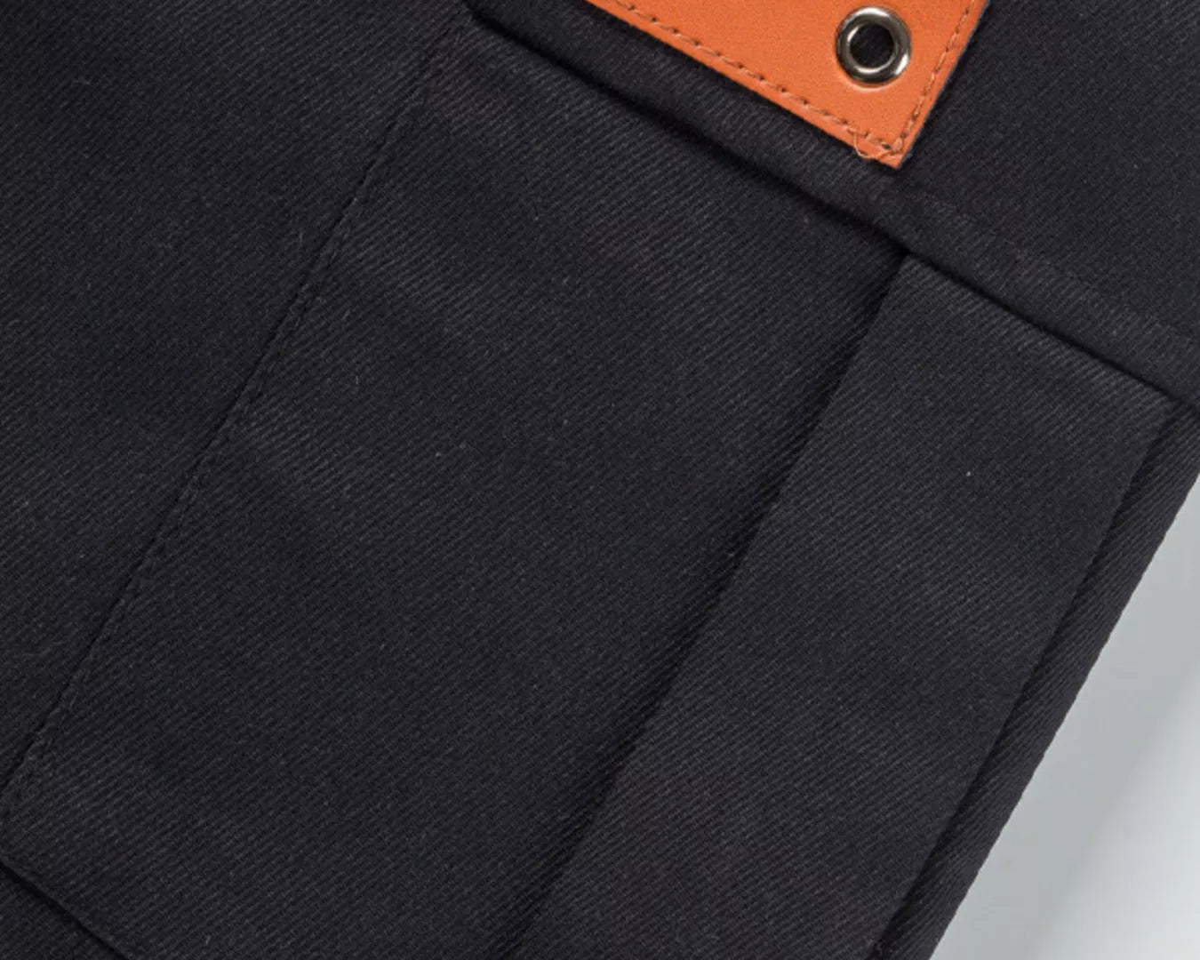 NEWYORKLISTED ATLAS MEN'S COLLECTION: Close-up of a black pocket with an orange leather patch on a white background
