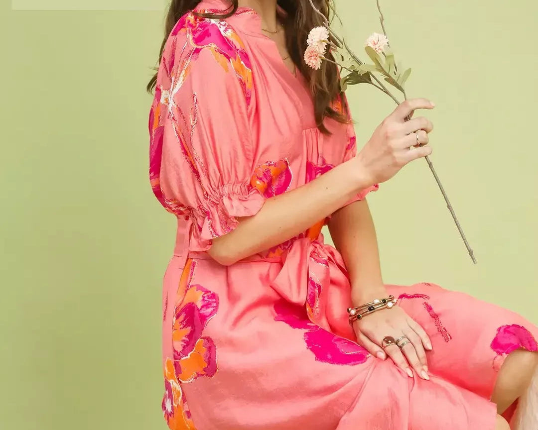 NEWYORKLISTED STYLE COLLECTION: Woman in a pink floral dress holding flowers against a light green background