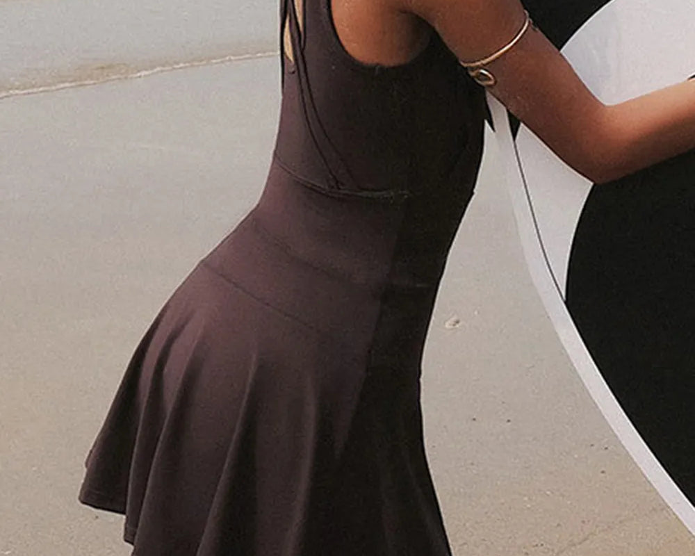 NEWYORKLISTED ACTIVEWEAR COLLECTION: Woman wearing a brown dress standing by a car on a road.