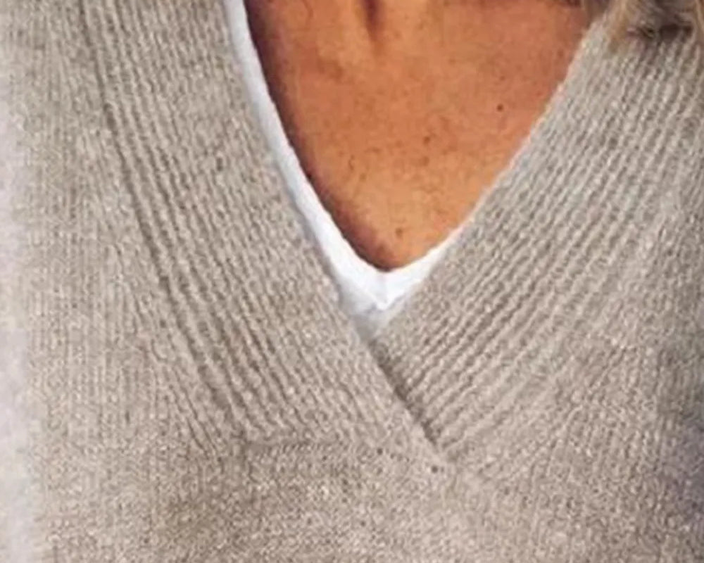 NEWYORKLISTED STYLE COLLECTION: Close-up of a person wearing a beige sweater over a white shirt.
