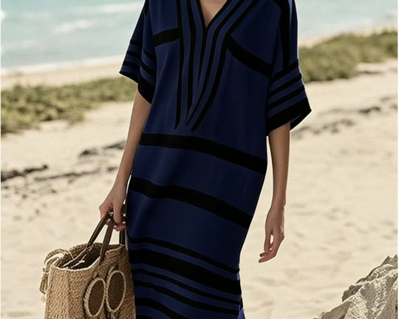 NEWYORKLISTED STYLE COLLECTION: Woman in a blue and black striped dress holding a straw bag on a beach.