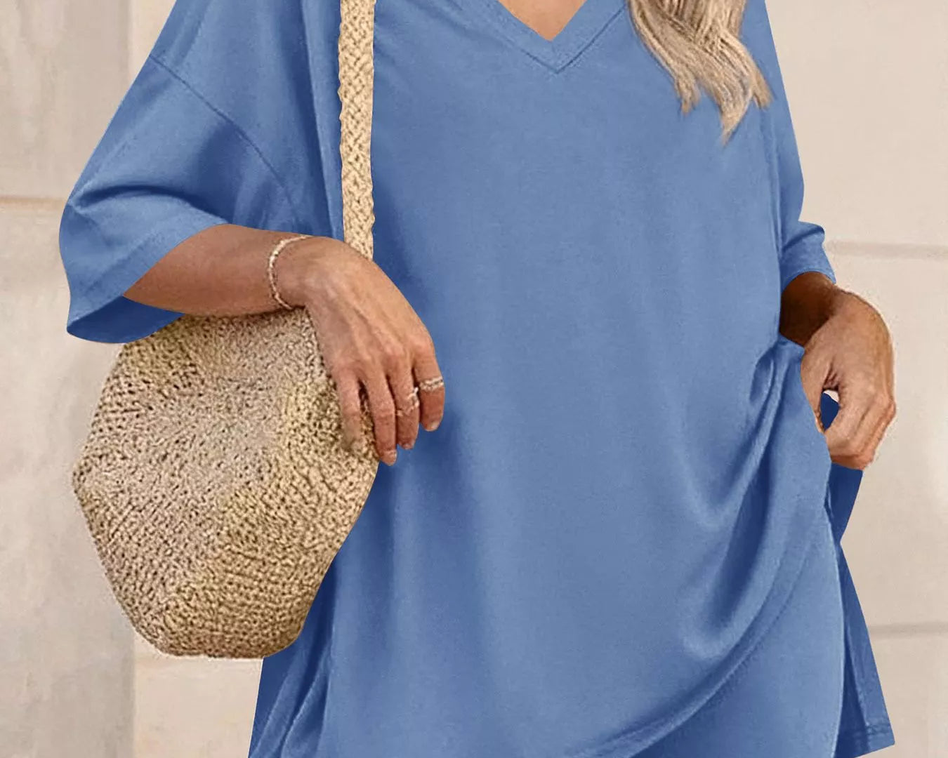 NEWYORKLISTED COMFORT COLLECTION: Woman wearing a blue outfit with a straw bag against a neutral background