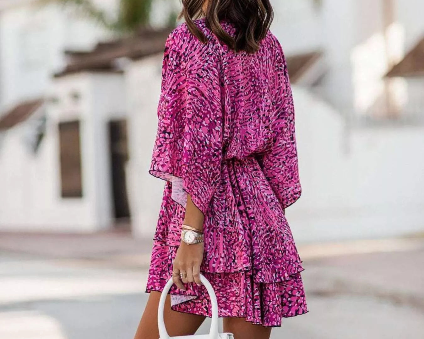 NEWYORKLISTED STYLE COLLECTION: Woman wearing a pink floral dress holding a white handbag in an outdoor setting.
