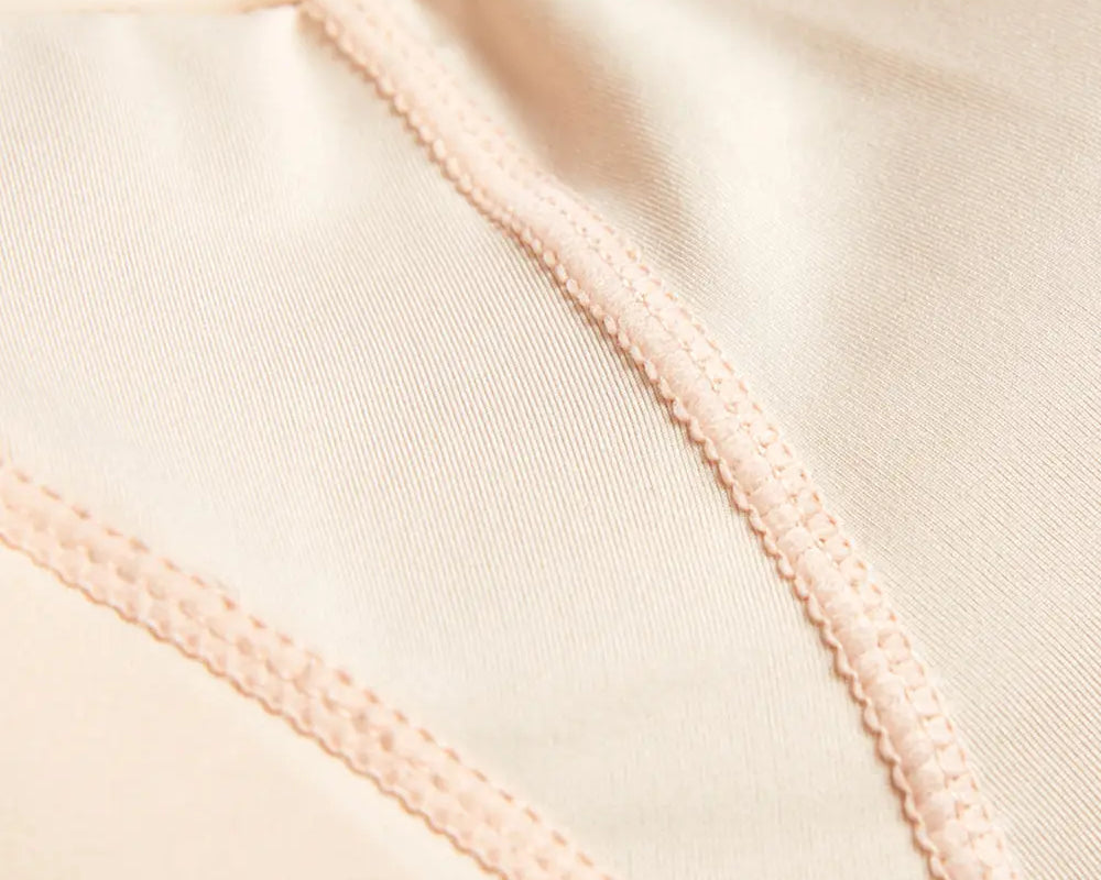 NEWYORKLISTED Intimate Apparel: Close-up of beige fabric with a focus on stitching detail